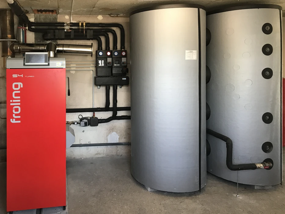 Local technique avec chaudière Froling rouge et réservoirs de stockage cylindriques gris