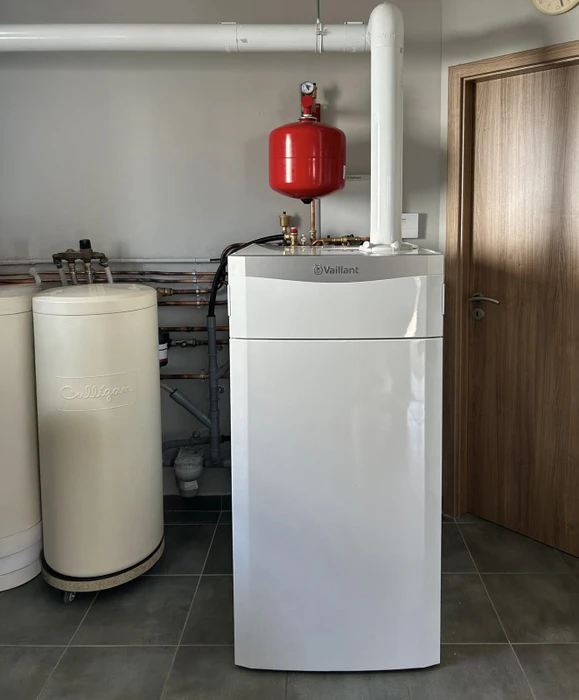 Chaufferie moderne avec chaudière à gaz Vaillant blanche équipée d'un vase d'expansion rouge et conduit d'évacuation
