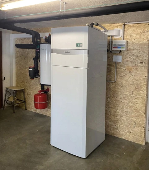 Cave technique avec chaudière à condensation Vaillant blanche au sol, raccordée à un système de chauffage