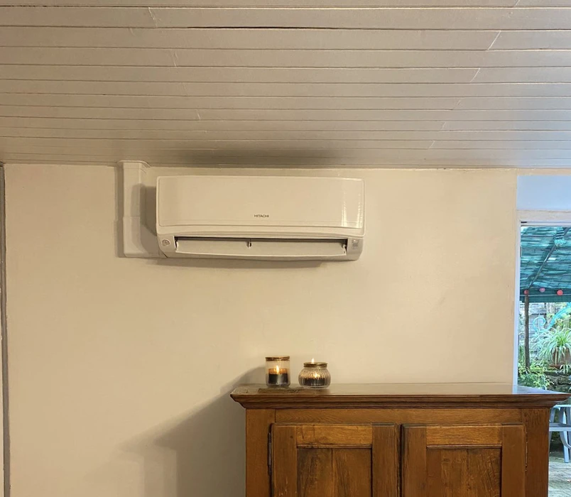 Intérieur résidentiel avec climatiseur mural Hitachi blanc installé sur mur beige