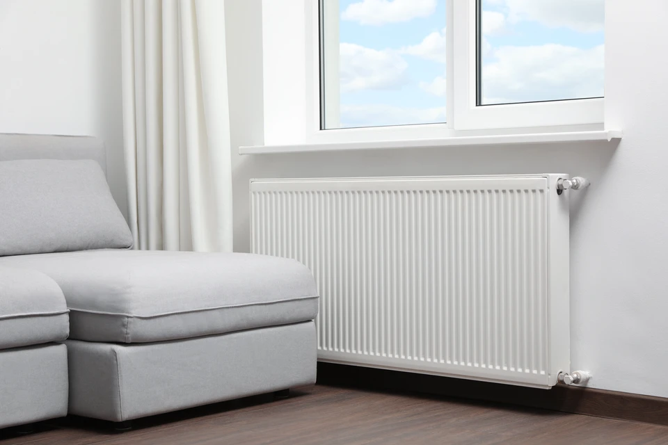 Intérieur résidentiel avec radiateur à ailettes blanches installé sous fenêtres en bois